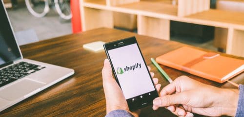 A person holding a phone with Shopify mobile app